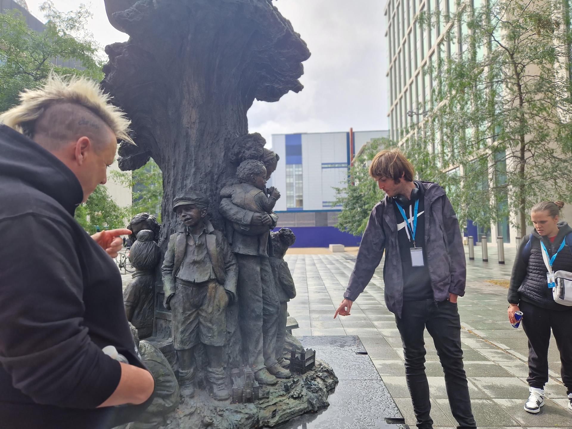 Tour guide pointing at Betty Cambell statue