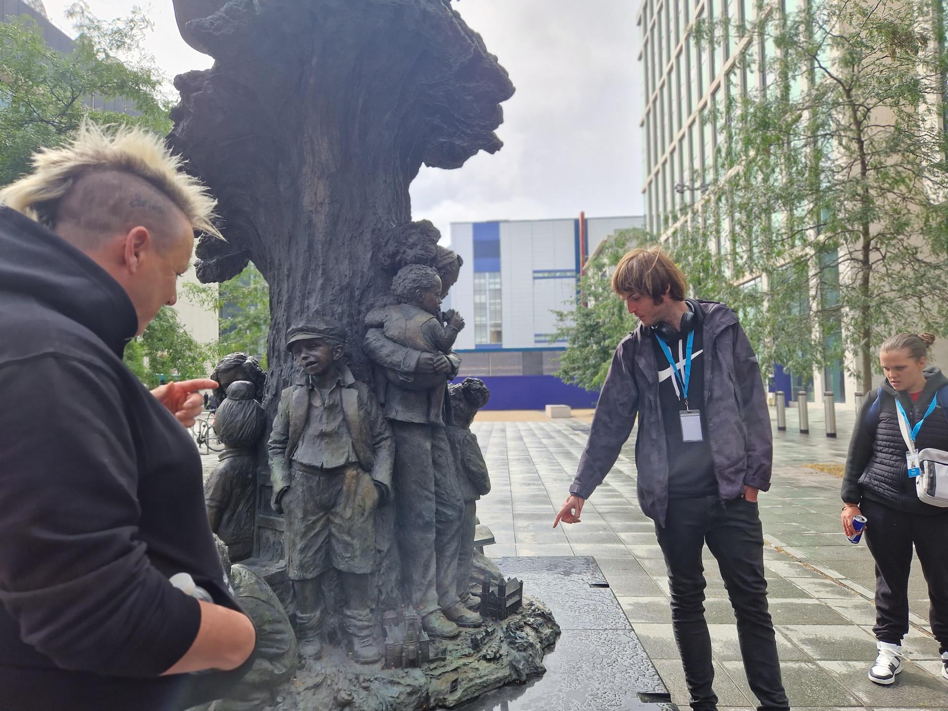 Tour guide pointing to Betty Cambell statue